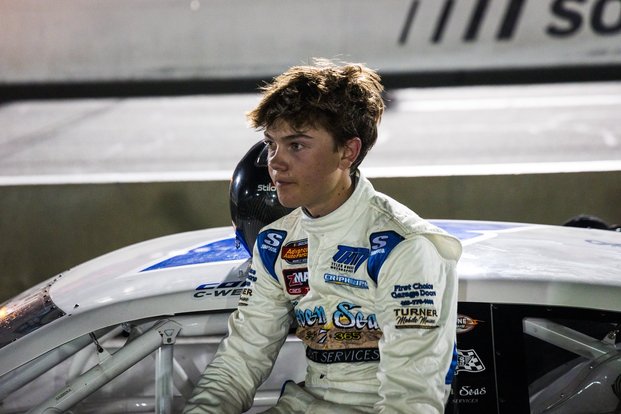 Conner Weddell sitting on the door of his #8W Late Model Stock Car at night